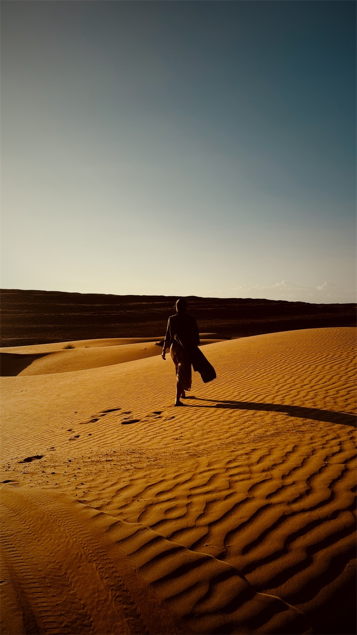 Cristiana walking across rippled sand dunes at golden hour