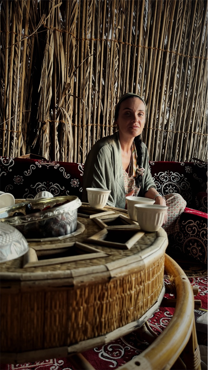 Cristiana in a palm-frond majlis with coffee cups on the table