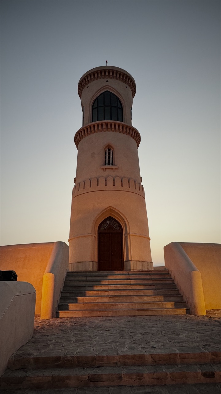 A sand-coloured tower with steps up to its door at dusk